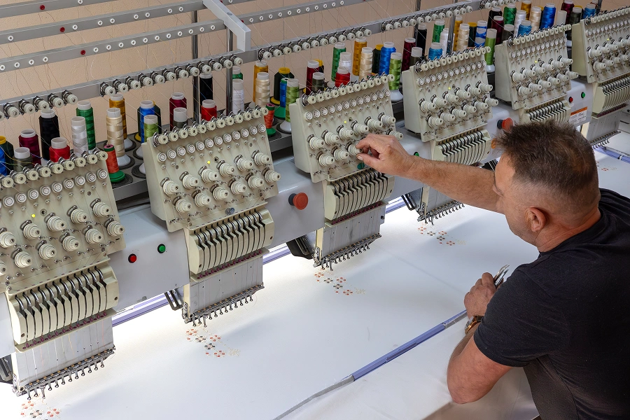 Man adjusting settings on embroidery machine.