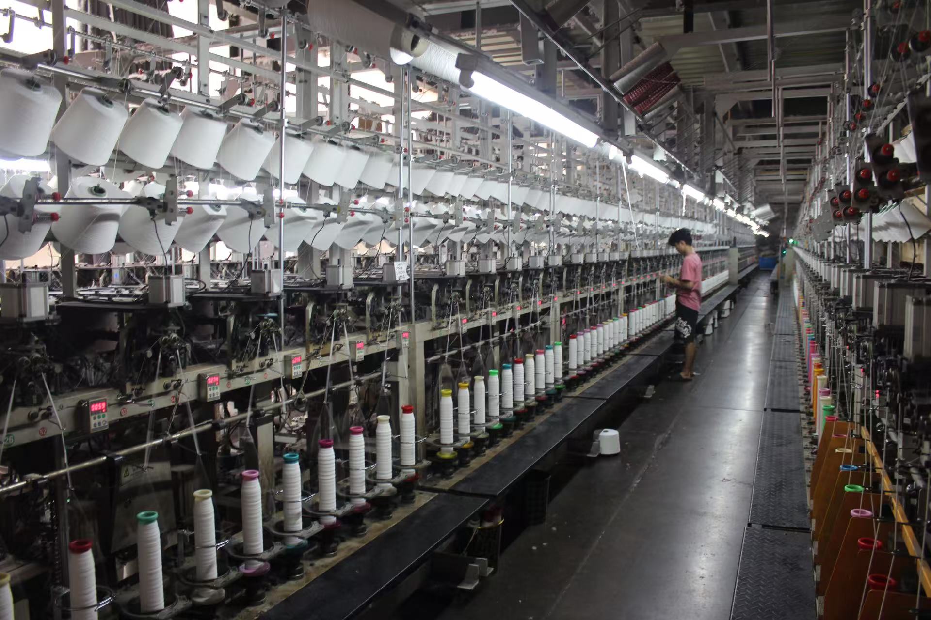 A worker operating a large textile machine in a factory.