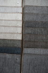 Close-up of textured fabric swatches in neutral tones arranged in two columns.