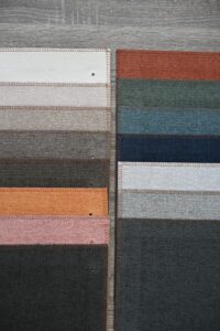 Fabric swatches in various colors arranged in rows on a wooden surface.