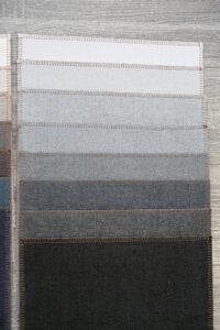 A vertical fabric sample card displaying various shades of gray from light to dark.