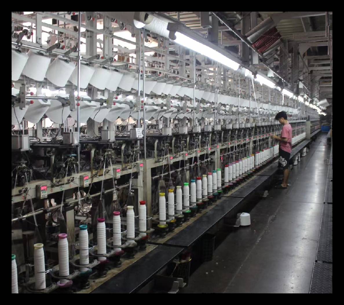 A large textile factory with spinning machines and a worker.